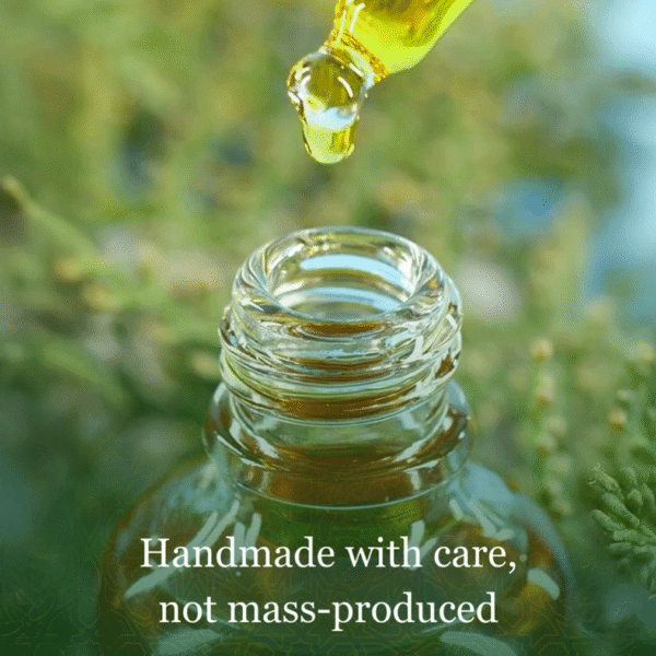 A dropper dispensing Z Secrets Secret Rosemary Hair Elixir into a small glass bottle, with the text organic & made with love, not mass-produced, over Z Secrets green Zelieg patterned background.